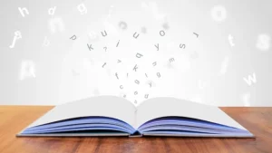 Open book with English letters flying above the page.