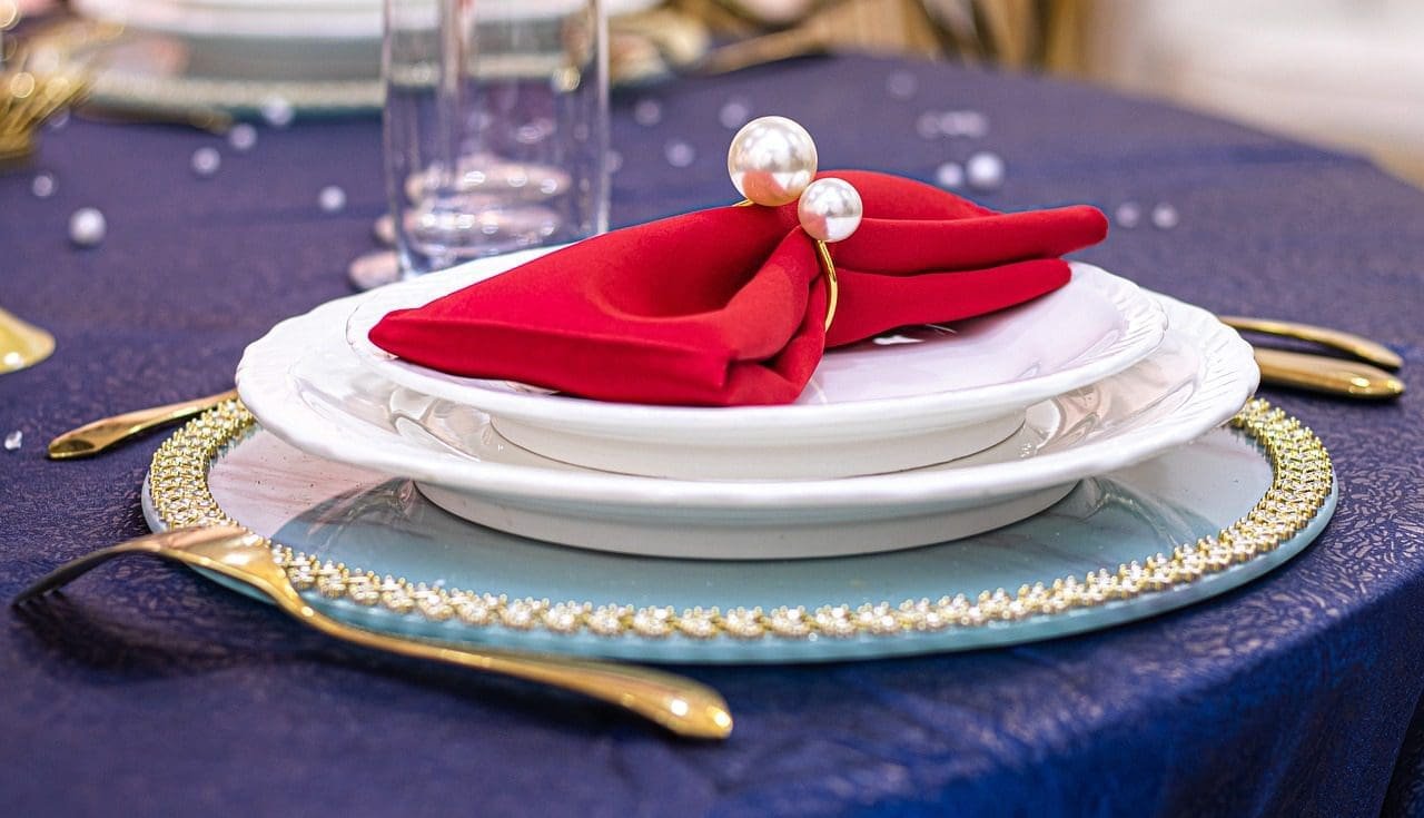 Place setting with napkin on top of plates.