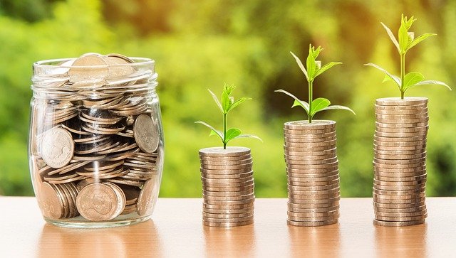 jar with coins, and three stacks of increasingly tall coins with little plants growing out of each stack